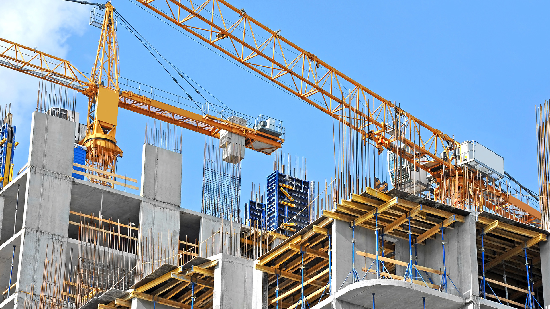 Crane-and-building-construction-site-against-blue-sky