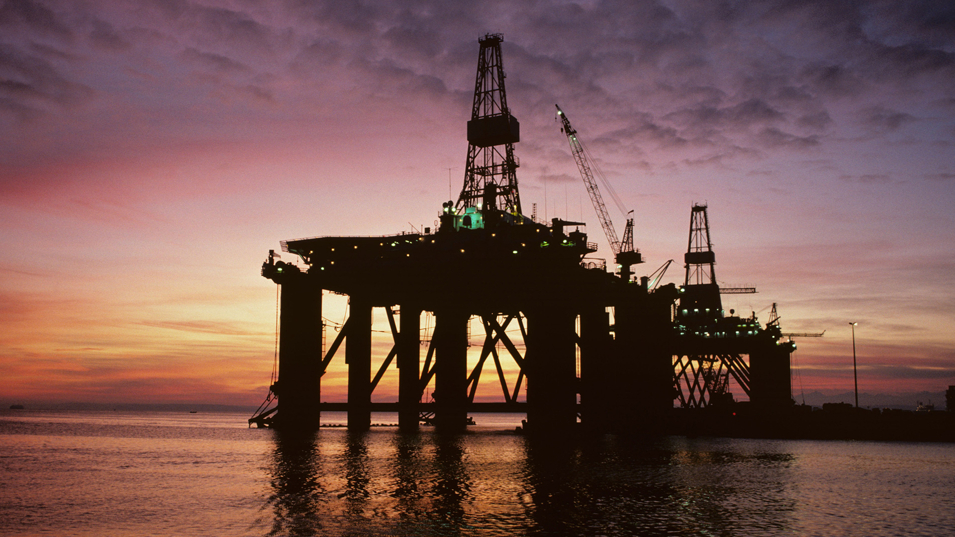 Oil derrick in ocean at sunset