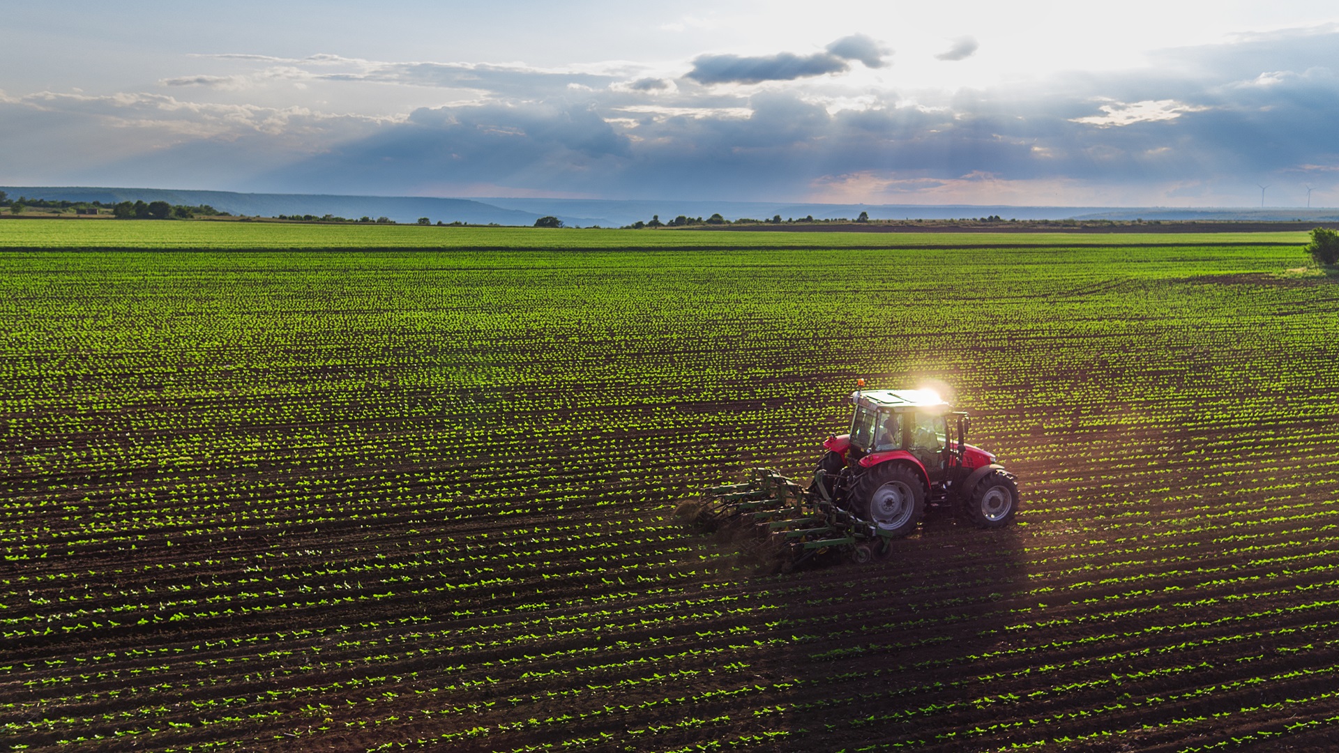 red tractor working on a lush green field