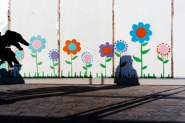 Photo called Red Riding Hood by Mark Heathcote showing flowers painted on a wall and silhouetted dogs' heads
