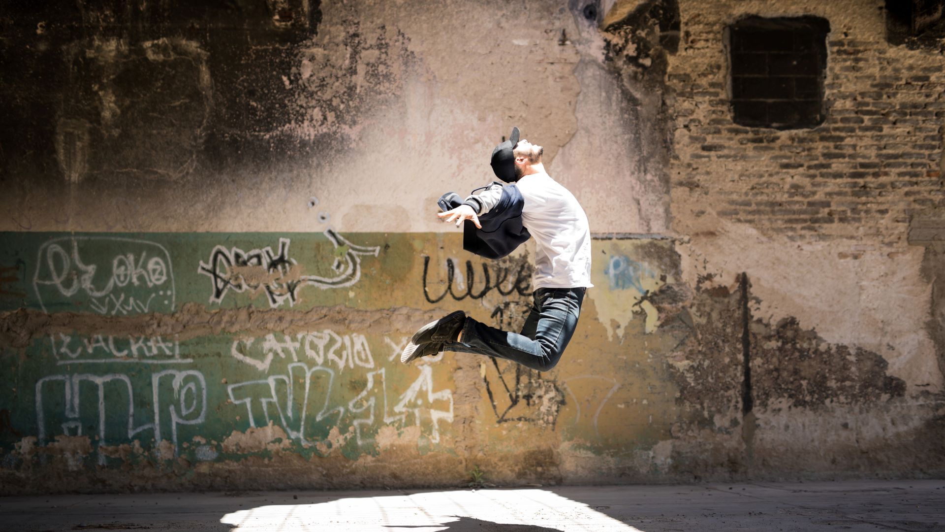 an urban dancer leaps with a wall behind