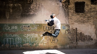 an urban dancer leaps with a wall behind