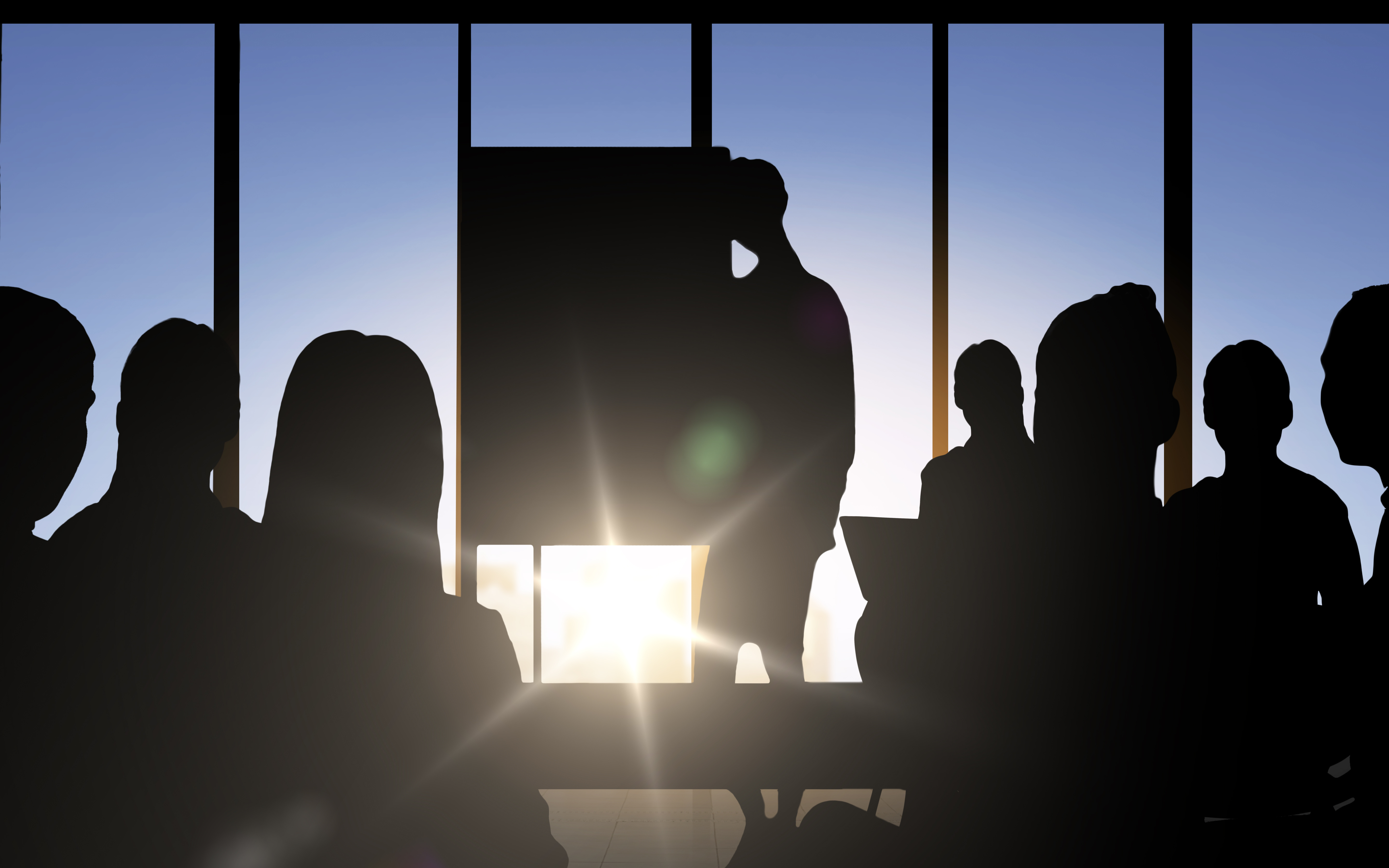 Silhouetted figures watch a presentation