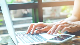 business-woman-working-with-a-laptop-computer-and-uses-a-cell-phone-in-the-office