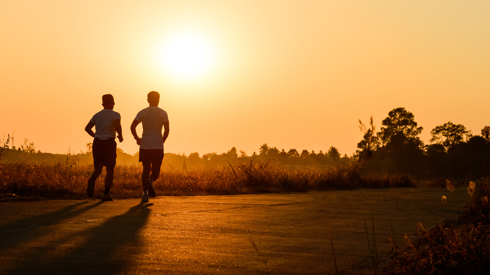 Two people running toward a sunset