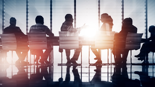 People sitting in a boardroom with sun shining in