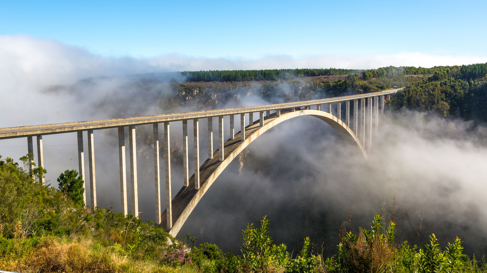 Bridge over fog between green hills