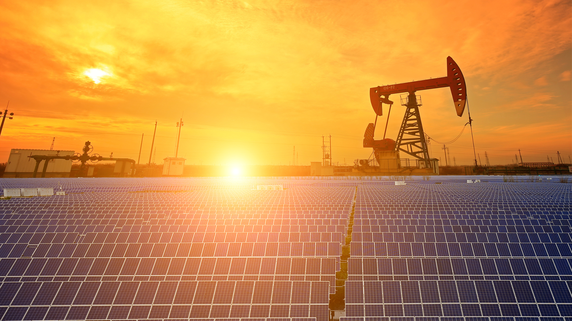 Solar panels near oil field overlooking a sunset