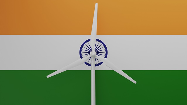 Large wind turbine in center with a background of the country flag of India