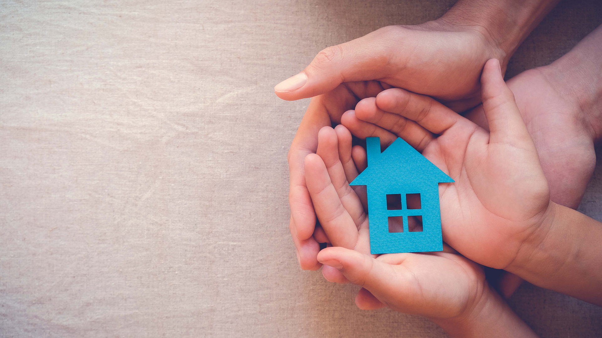 Hands holding a house made of paper