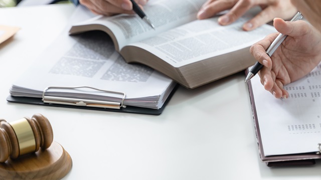 two people looking at a law book with a gavel on the table