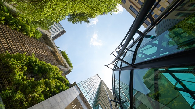 Low angle shot of modern glass buildings and green with clear sky background