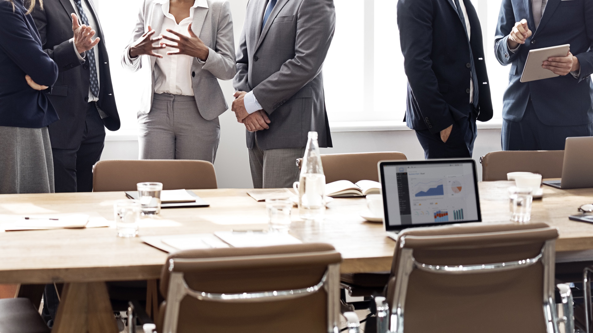 people-in-suits-talking-around-brown-table