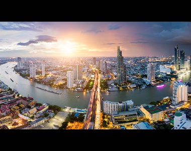 Aerial view of Bangkok skyline and skyscraper with light trails on Sathorn Road center of business in Bangkok downtown. Panorama of Taksin Bridge over Chao Phraya River Bangkok Thailand at sunset