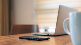 Employee workstation with a phone, laptop and coffee mug on the desk