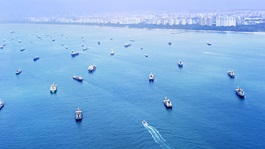 Various industry ships line the coast