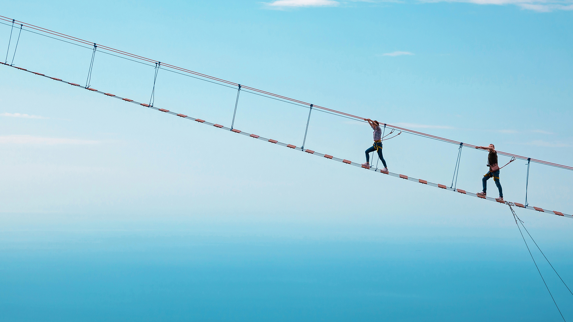 Two people walking on a rope bridge