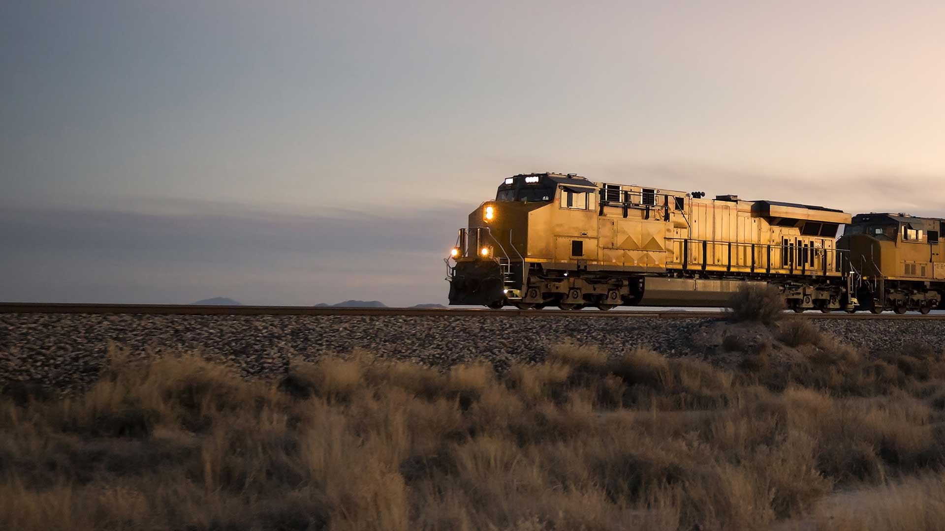cargo train travelling through rural area at twilight