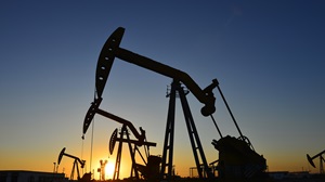 A line of three oil drills at sunset.