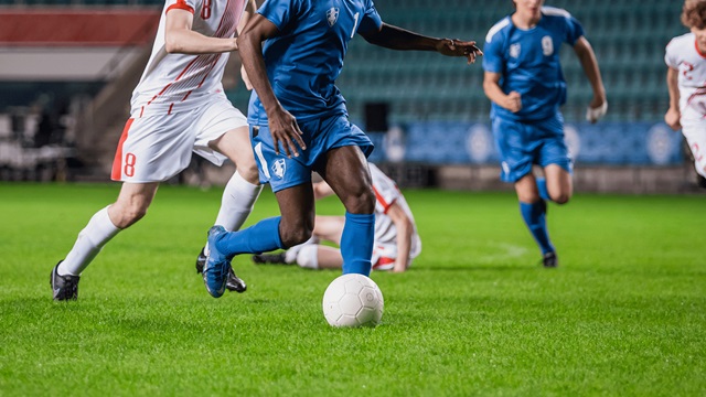 A footballer dribbles with the ball