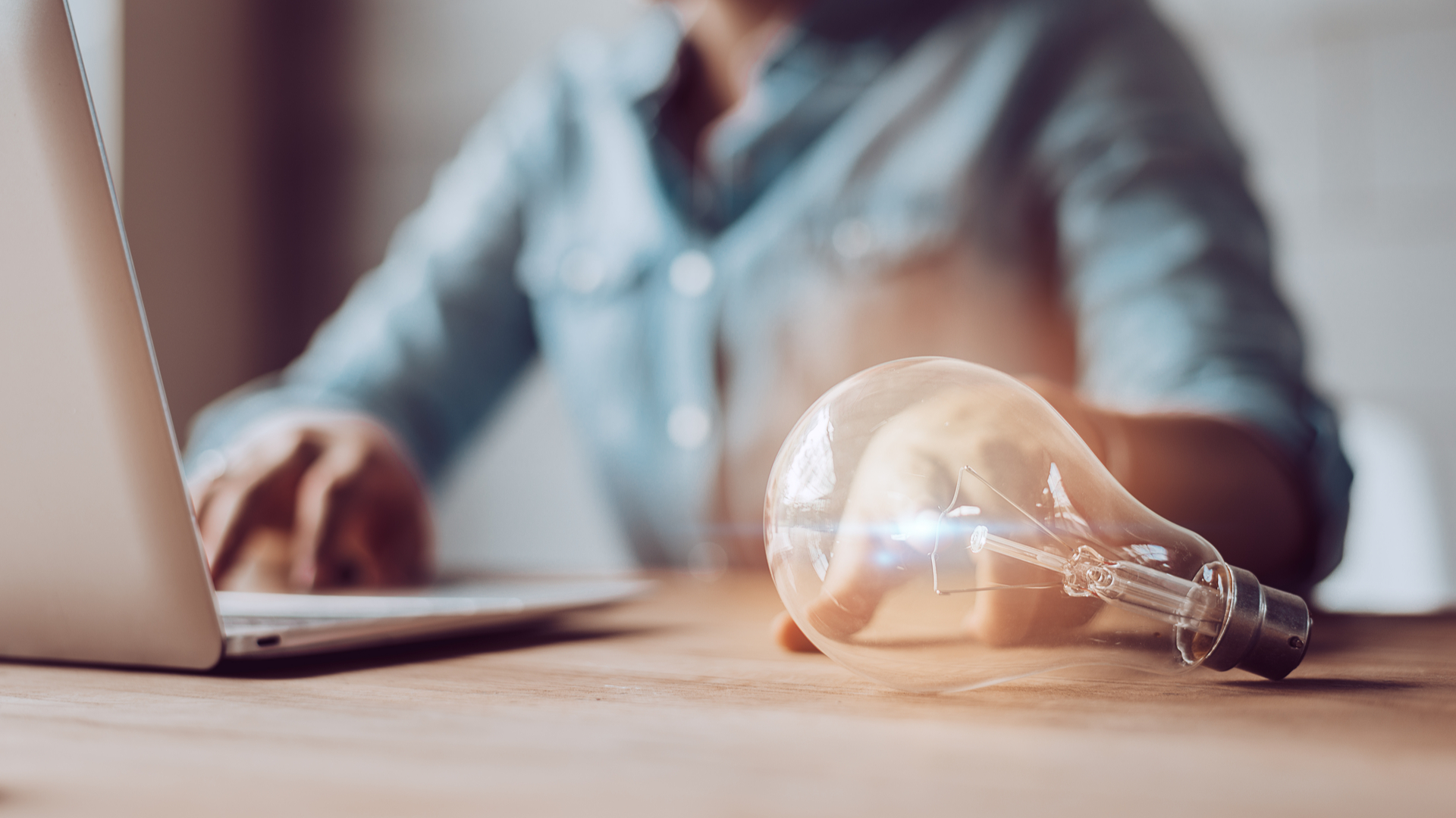 light bulb with woman working on laptop