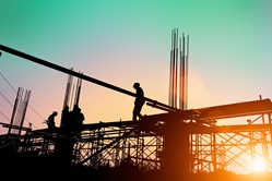 Silhouette of construction workers working on scaffolding 