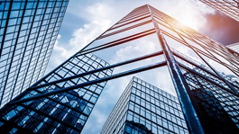 Glass office building with sky and other towers in its reflection