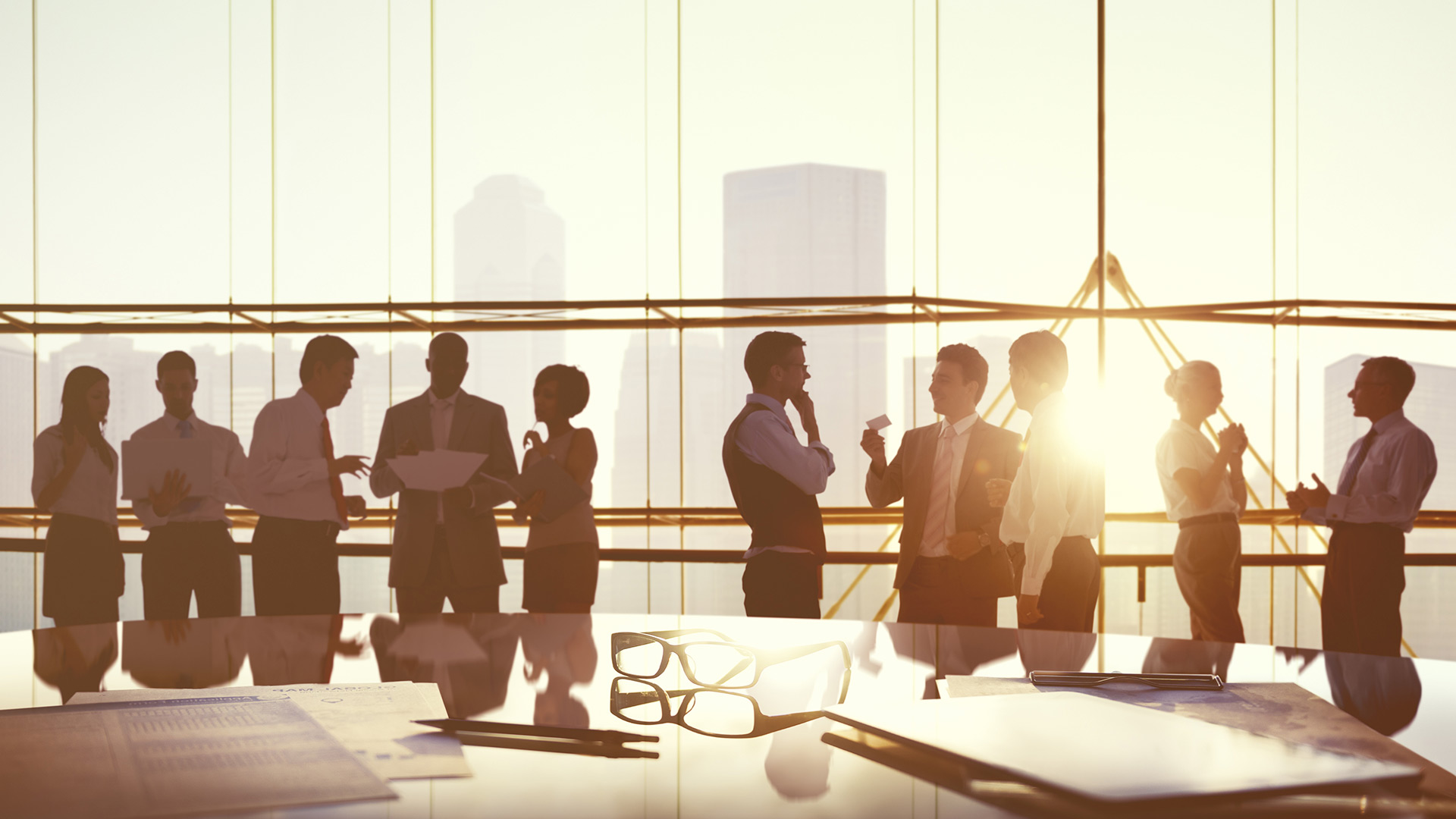 Boardroom with people in a standing meeting, sun setting in background