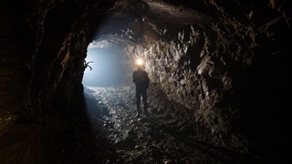Un mineur dans un tunnel de mine avec sa lampe frontale allumée