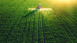 Aerial view of farming tractor spraying a field