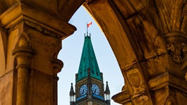 Vue du drapeau canadien sur l'immeuble du Parlement à travers l'arche d'un autre immeuble