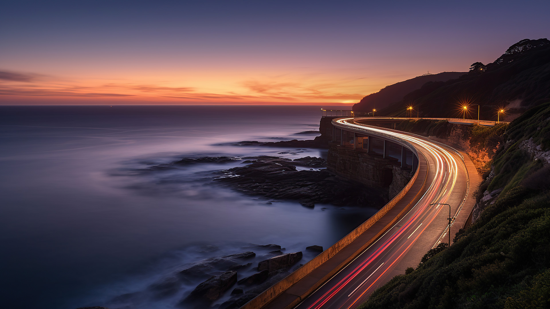 Sunset over the Sea cliff bridge along Pacific ocean coast with lights of passing cars