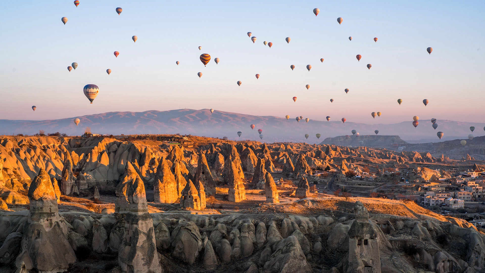 Eroded and volcanic-like terrain with hot air balloons in the sky