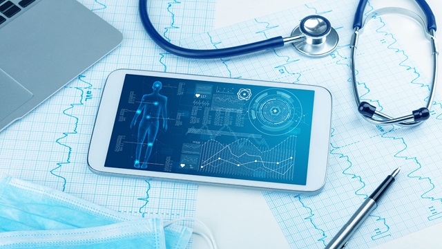 Medical desk with a tablet, pen, laptop, stethoscope and charts