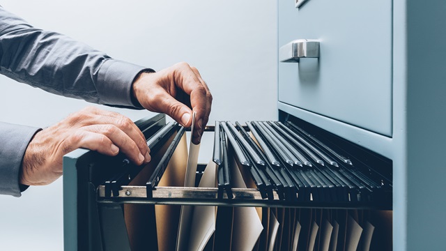 Person searching for files in a filing cabinet drawer