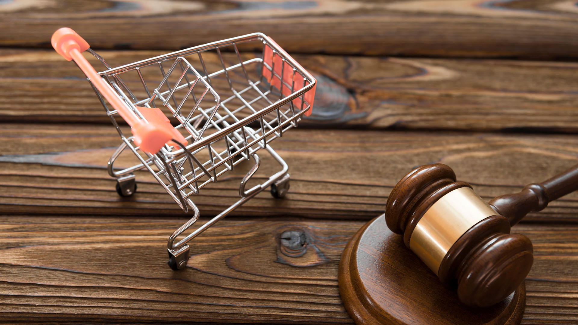 A miniature shopping cart and gavel sitting on top of wooden planks