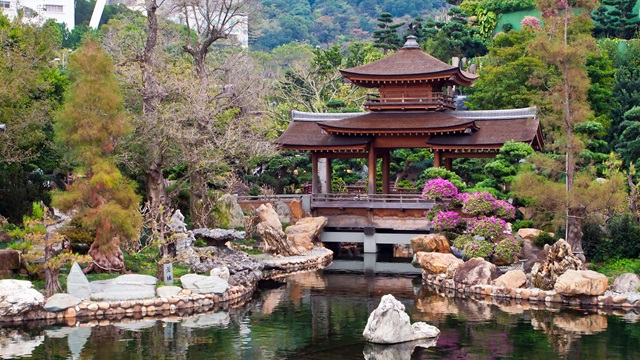 A peaceful pond lined with rocks in front of a small gazebo structure