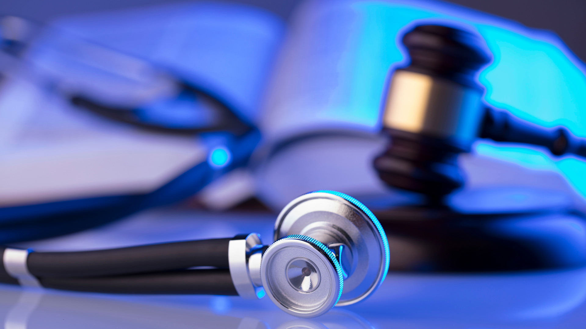 Stethoscope and gavel on a desk with a glossy finish