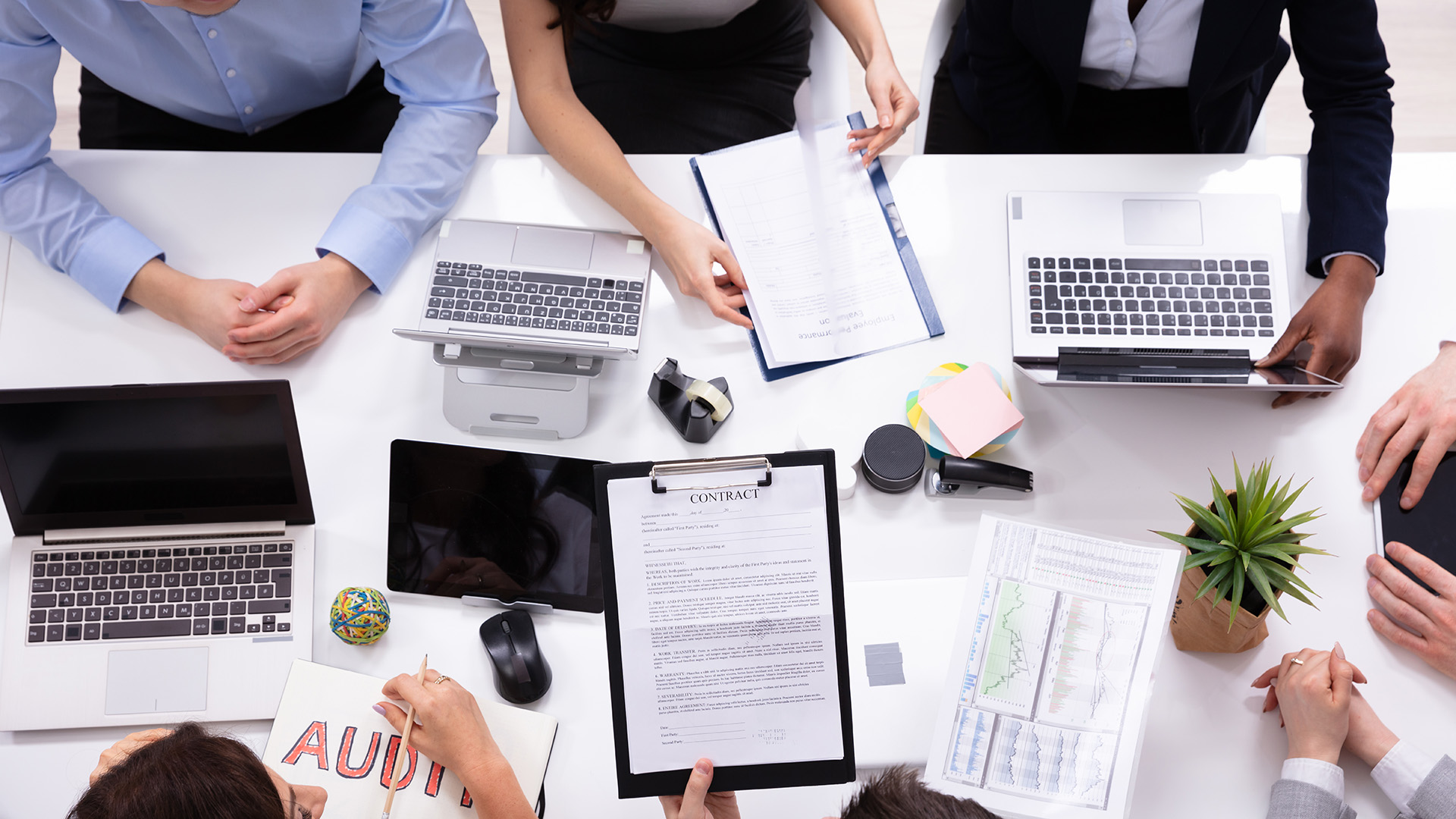 Group of employees in a meeting with laptops and notes